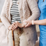 Elderly woman walking with help from a nurse