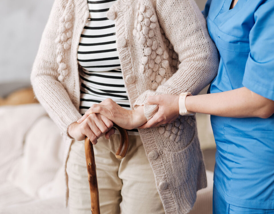 Elderly woman walking with help from a nurse